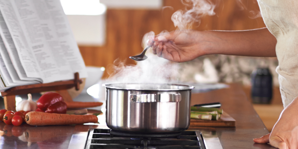 Chef holding spoon of steaming broth