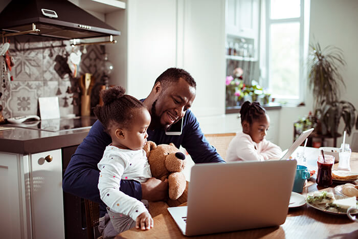 father holding his daughter while talking on the phone